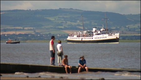 Holidaymakers sitting on the jetty watch the Balmoral in Bridgwater Bay