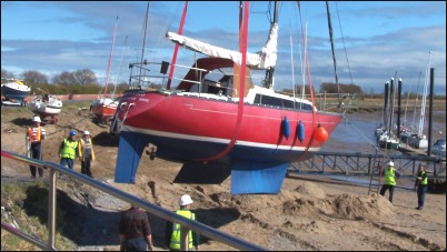 A boat is carefully moved into position by the crane and men with ropes