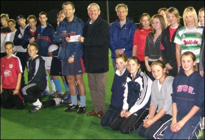 The cheque is handed over alongside the two teams