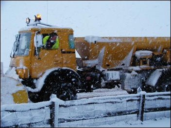 A snow gritter in bad weather