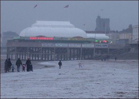 A family braves the cold during a walk along the snow-covered beach at Burnham