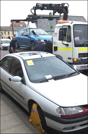 One car is clamped and another is lifted onto a tow truck outside the Burnham RNLI station