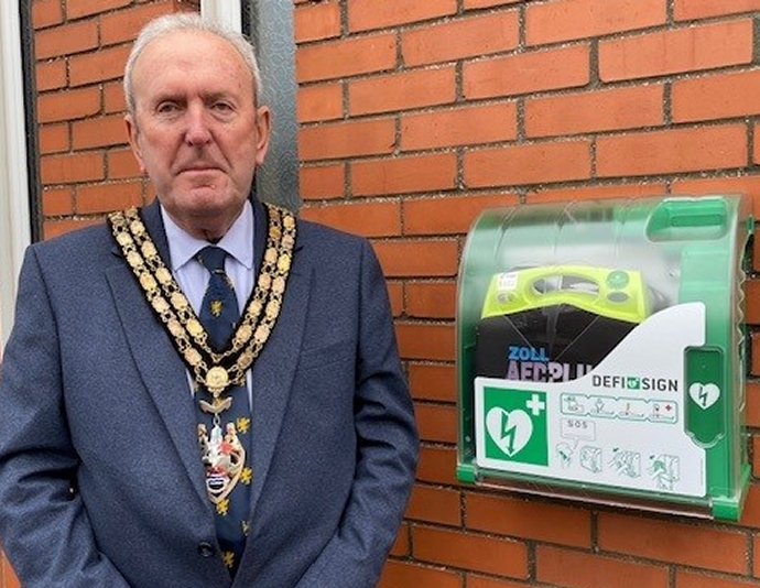 Mayor of Burnham-on-Sea & Highbridge Town Council, cllr Mike Facey, stodd by new defib outside Council offices